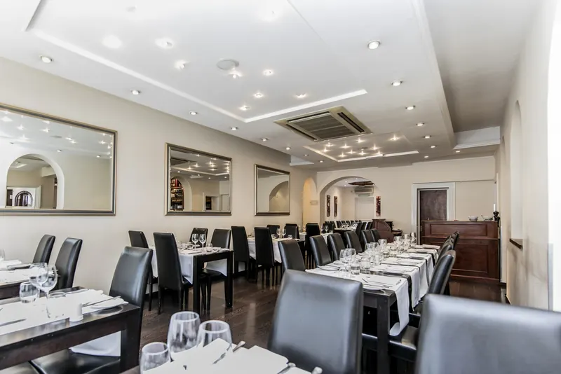 The dining room: white-clothed tables, dark leather chairs and arched mirrors along the walls