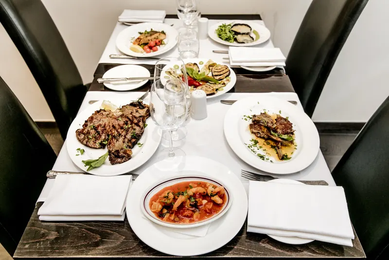 A table for two laid with grilled meats, vegetables and a seafood stew