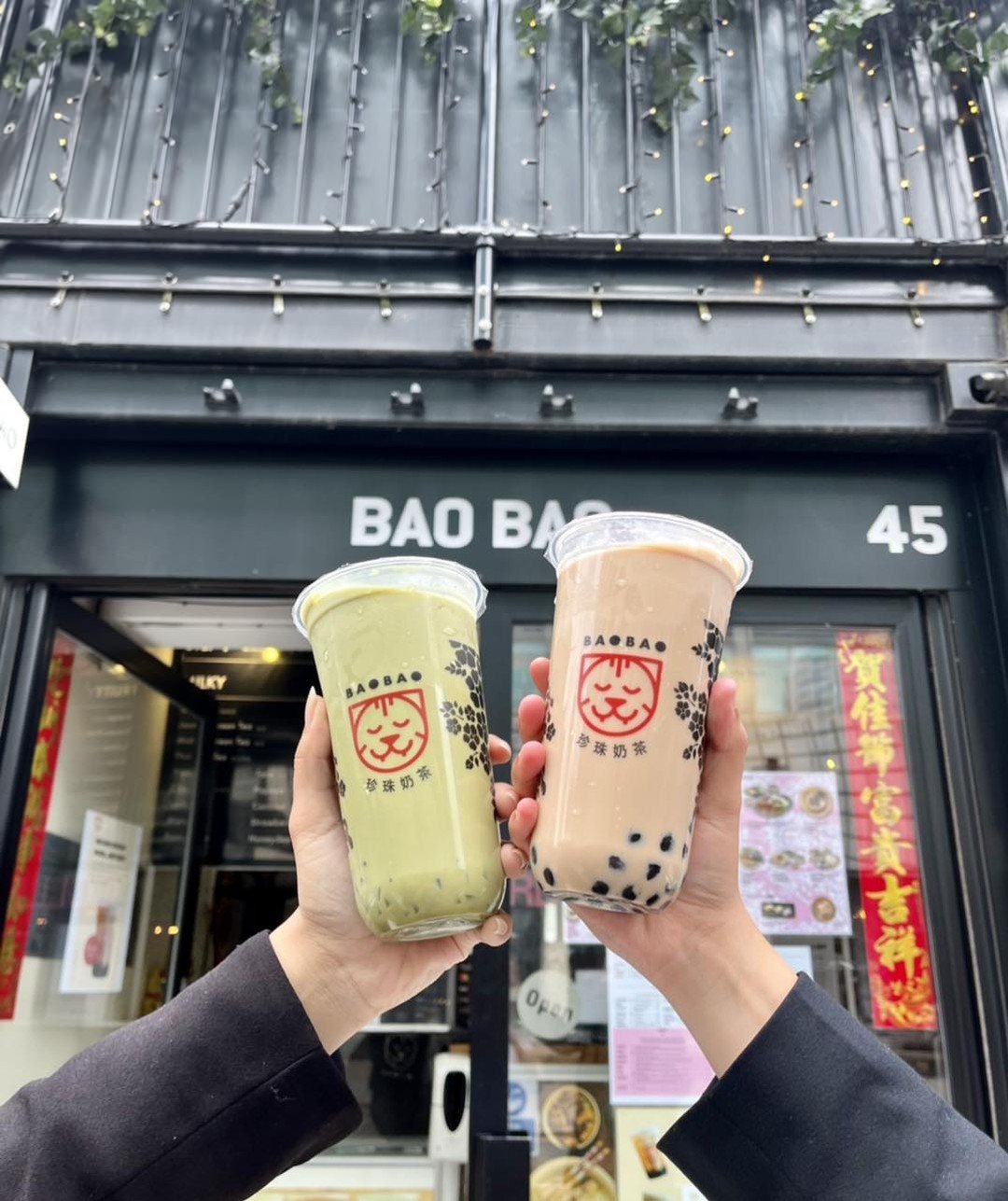 Two BaoBao bubble teas raised in front of the shop at Boxpark Croydon