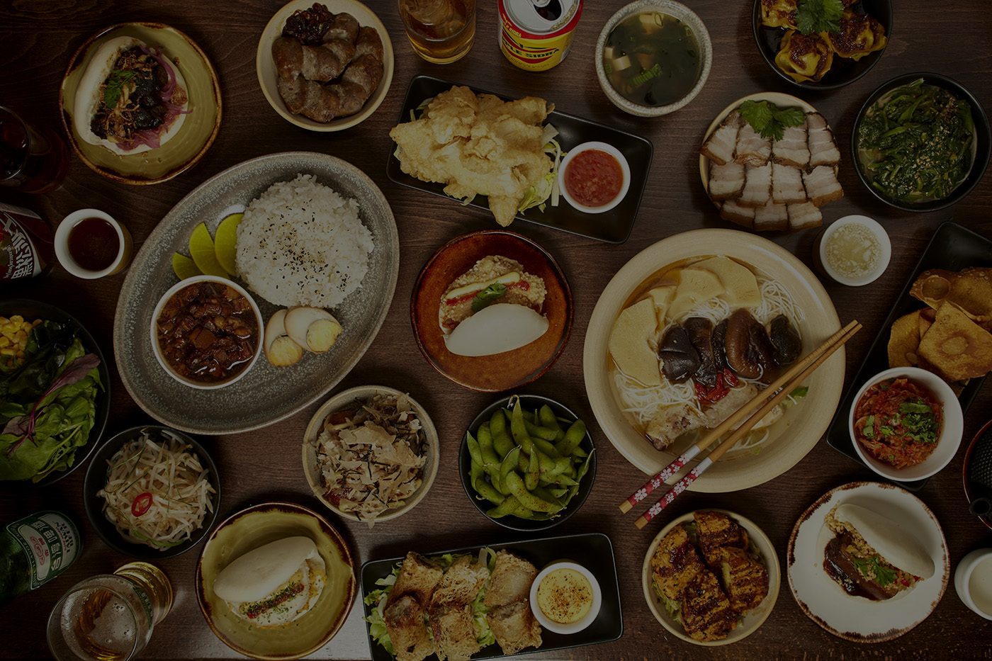A table spread of Taiwanese dishes: braised pork rice, beef noodle soup, fried chicken and bao