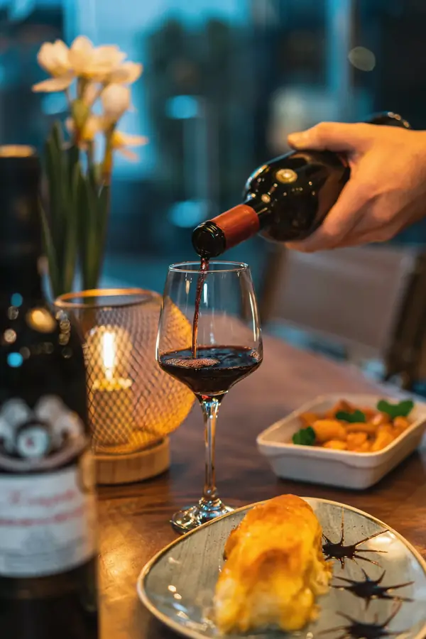 Red wine being poured at a candlelit table