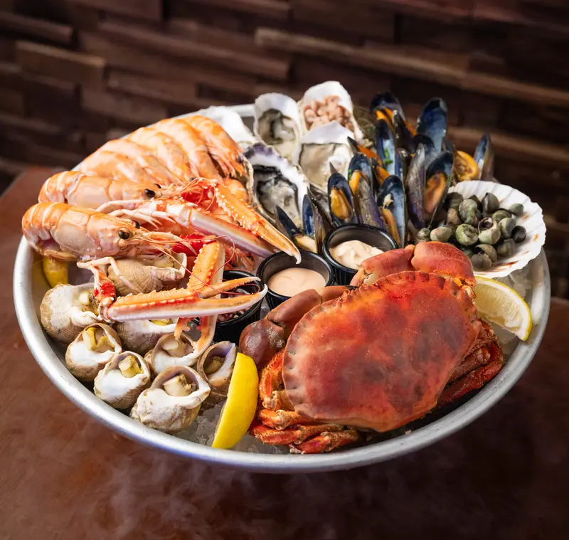 A round fruits de mer platter with crab, langoustines, oysters, whelks and mussels